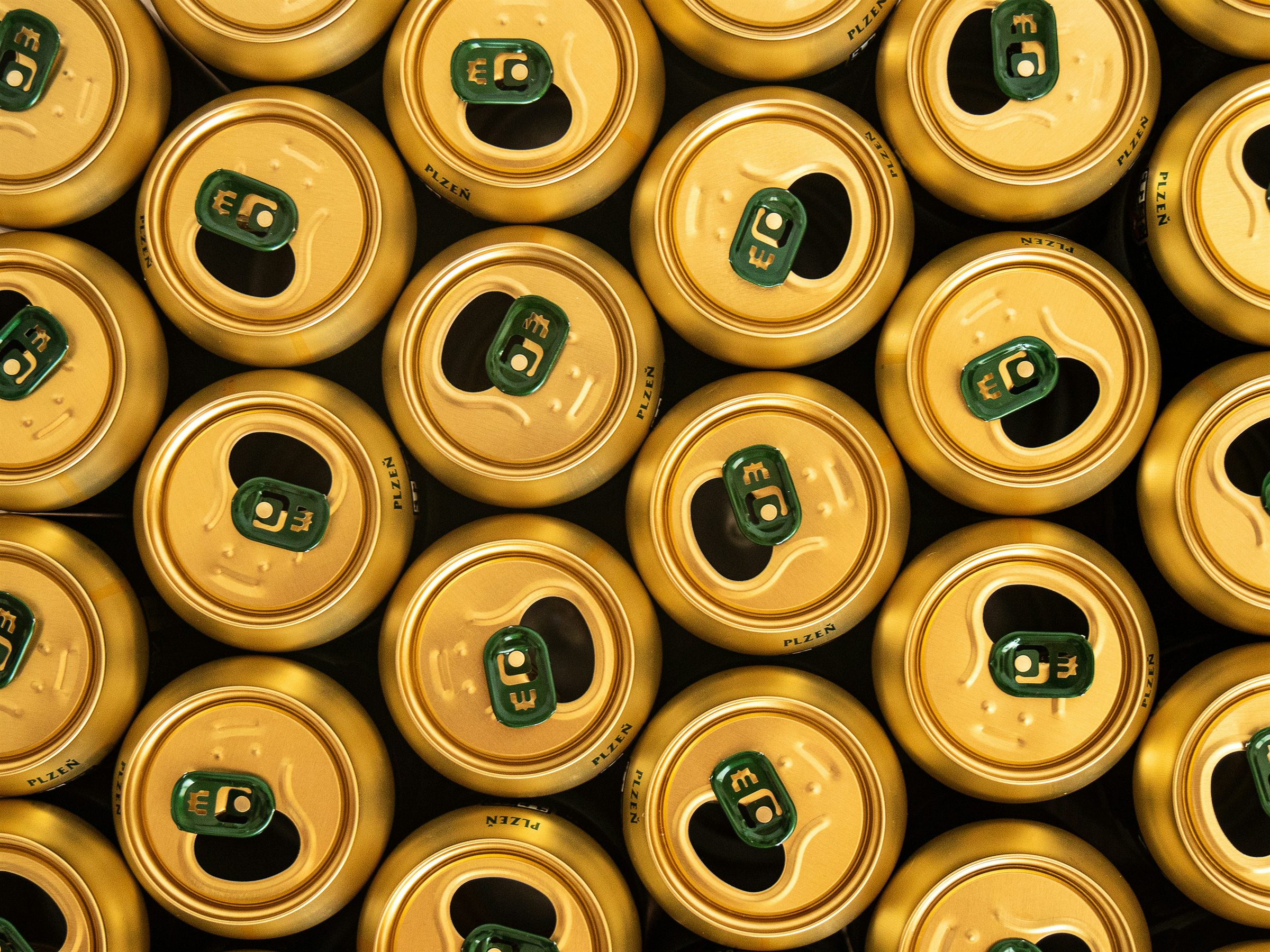 An overhead view of rows of opened gold beer cans