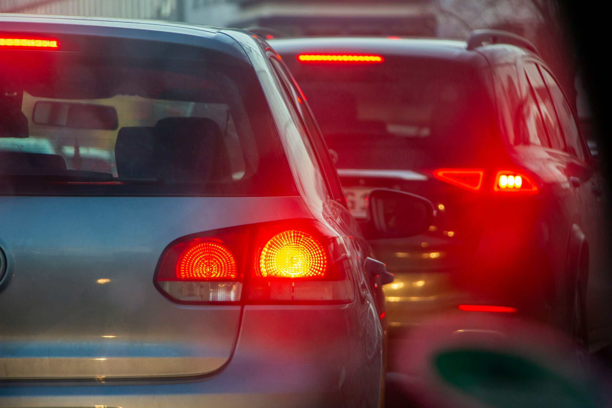 Cars queued closely together with their brake lights illuminated